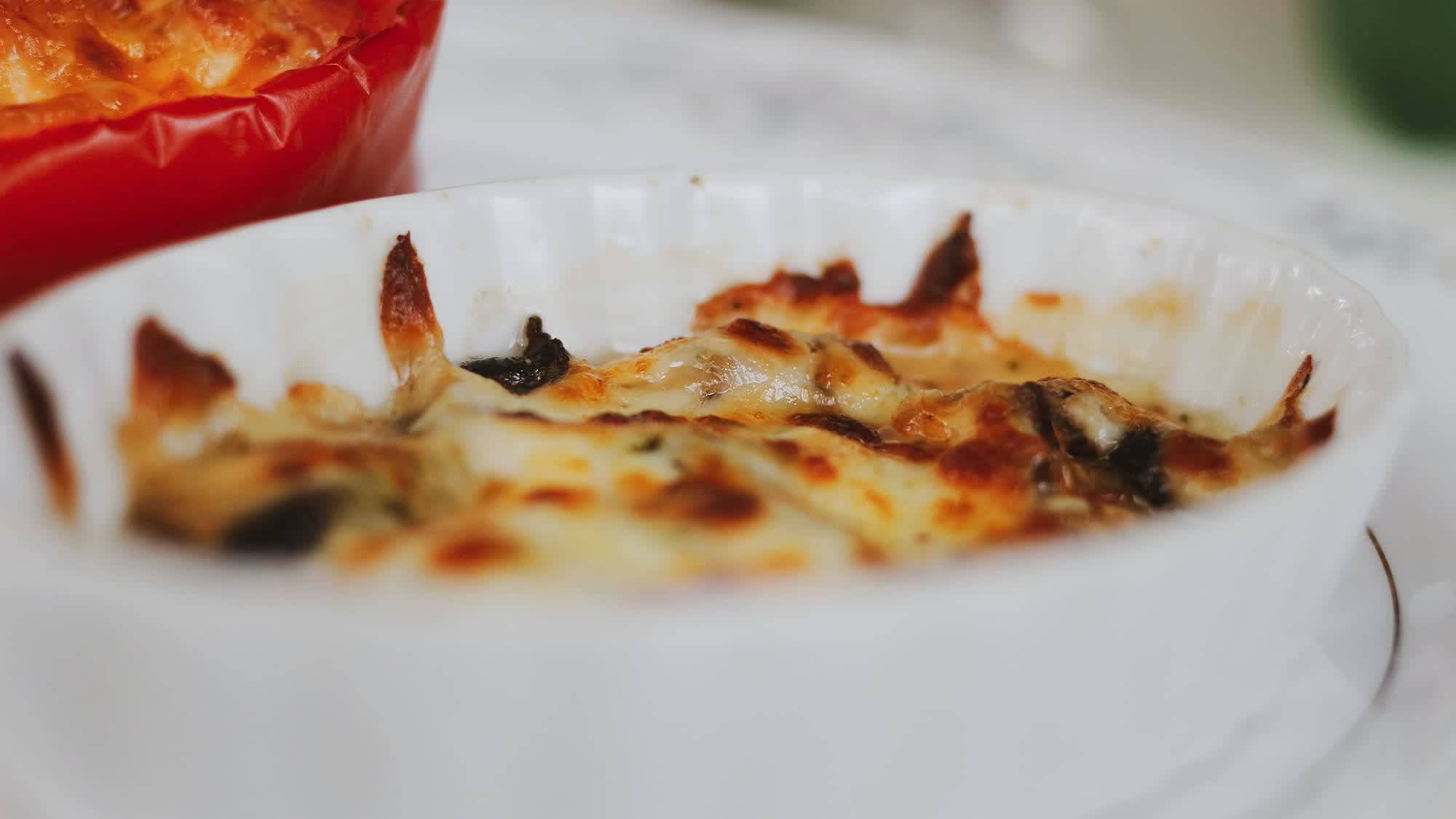 Überbackene Eimasse mit Spinat und gebräunter Käsekruste in einer weißen Form
